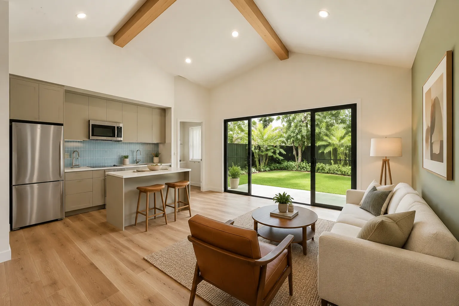 Compact open-plan interior with kitchenette, vaulted ceiling, and garden view