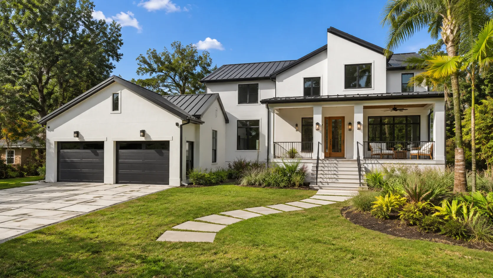 Modern-farmhouse style home with metal roof, front porch, and tropical landscaping