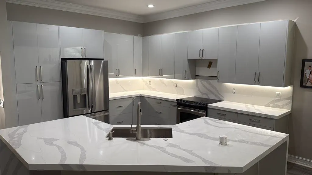 Completed grey high-gloss kitchen with quartz waterfall island and under-cabinet lighting