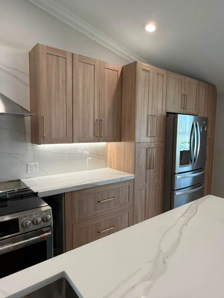 Installed light-oak kitchen with calacatta quartz backsplash and under-cabinet lighting