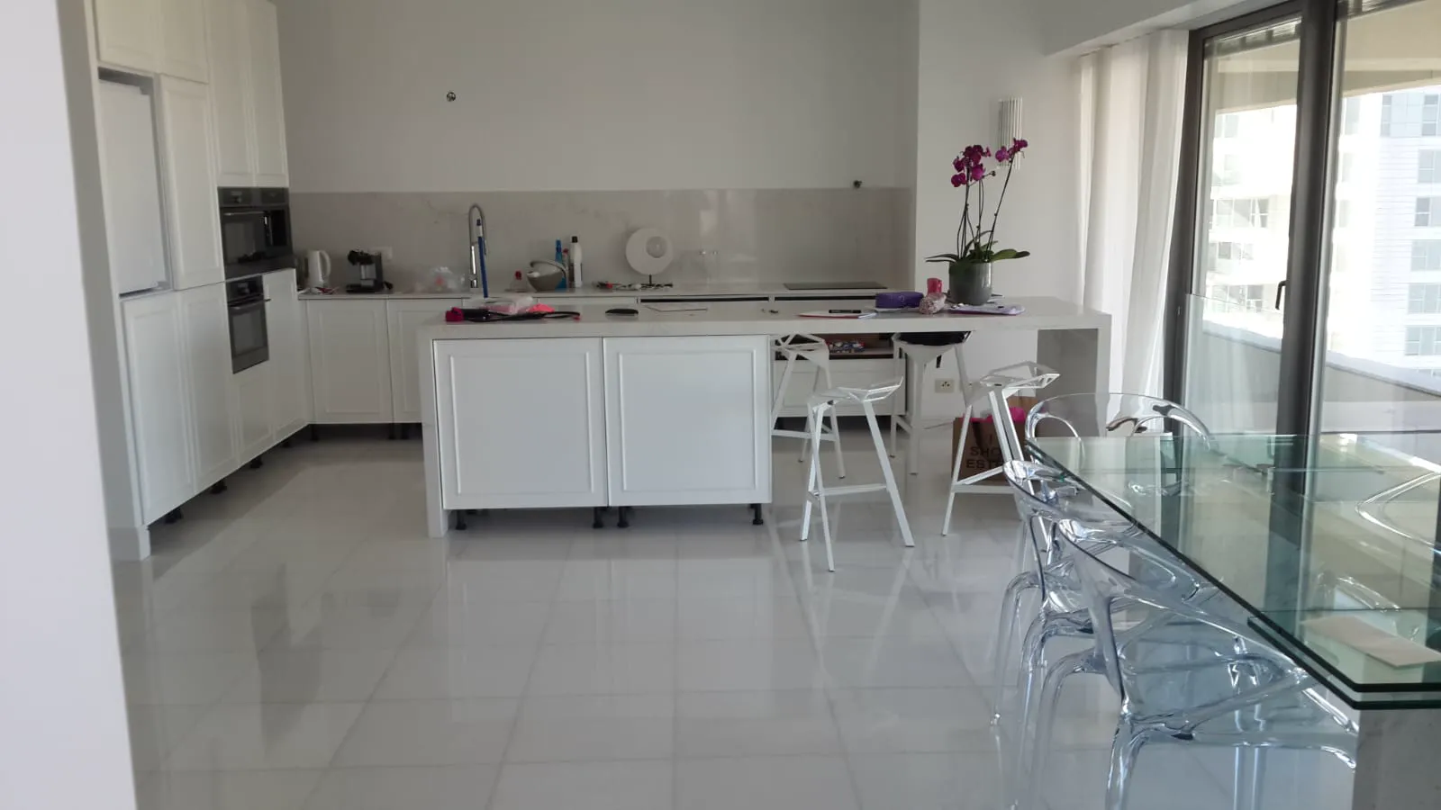 Completed white apartment kitchen with island and polished tile floor