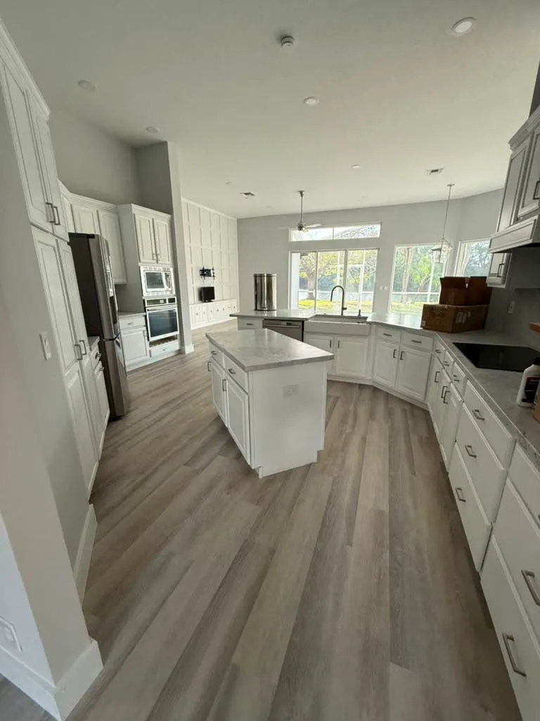 Completed white kitchen with island and new luxury-vinyl-plank flooring