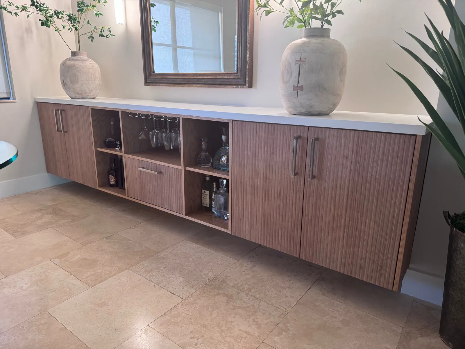 Custom floating walnut credenza with glassware storage and white countertop